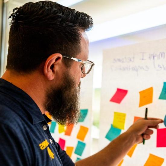 A man attaches sticky notes to a large white paper adhered to a large window.