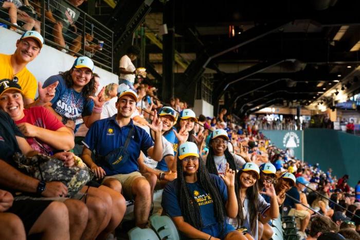 Fans in the stands at a baseball game posing f或者一个 photo.